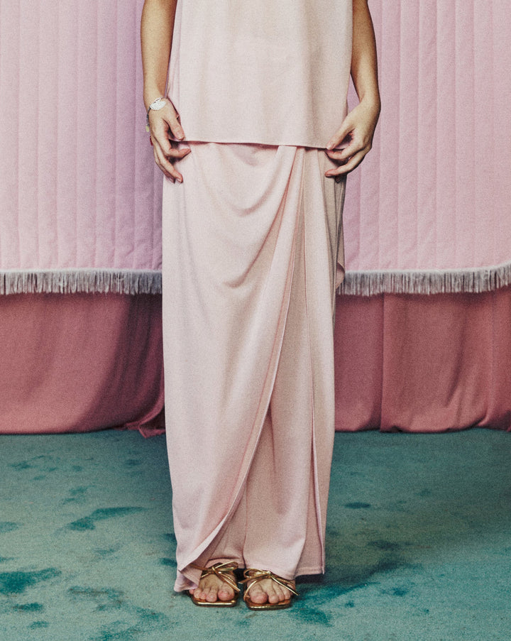 Woman in a pink dress standing in front of a heart-shaped curtain